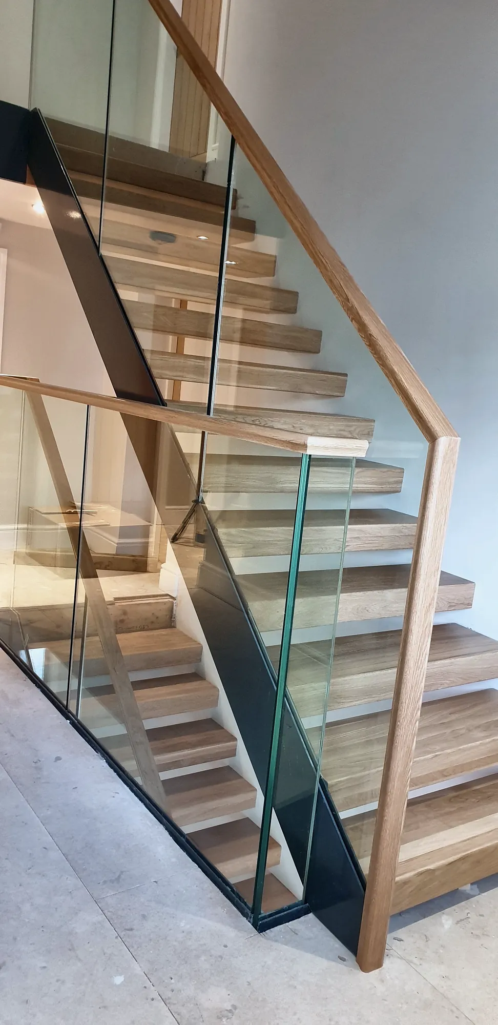 Glass balustrade and oak handrail rising to the landing