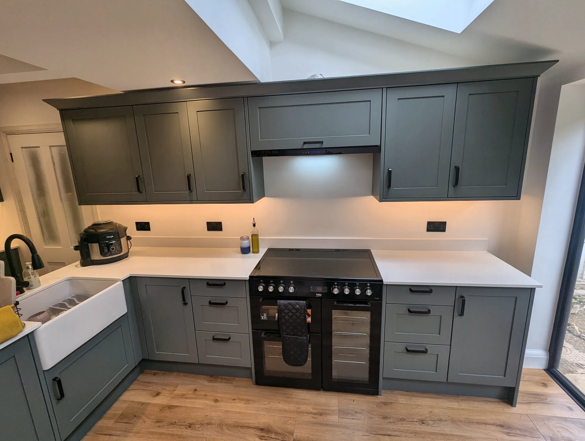Dark green Shaker kitchen with a Belfast sink and range cooker