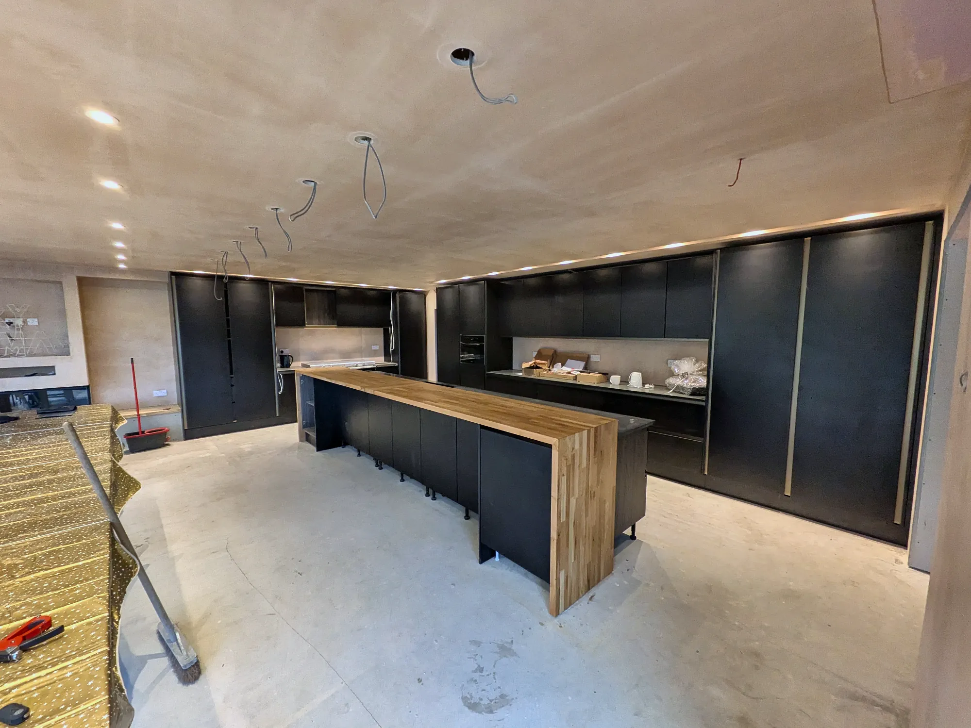 Long run of tall units and the island beneath a line of downlights