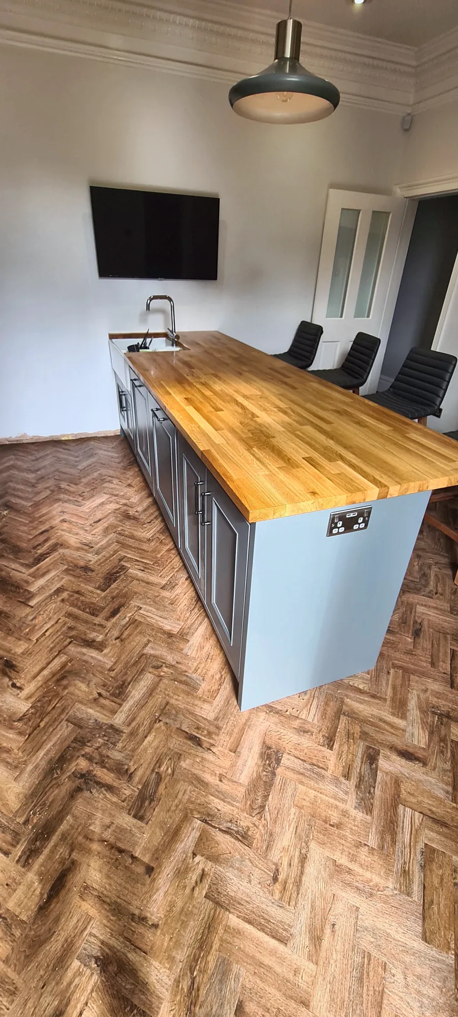 Grey-green kitchen with a long oak-topped island