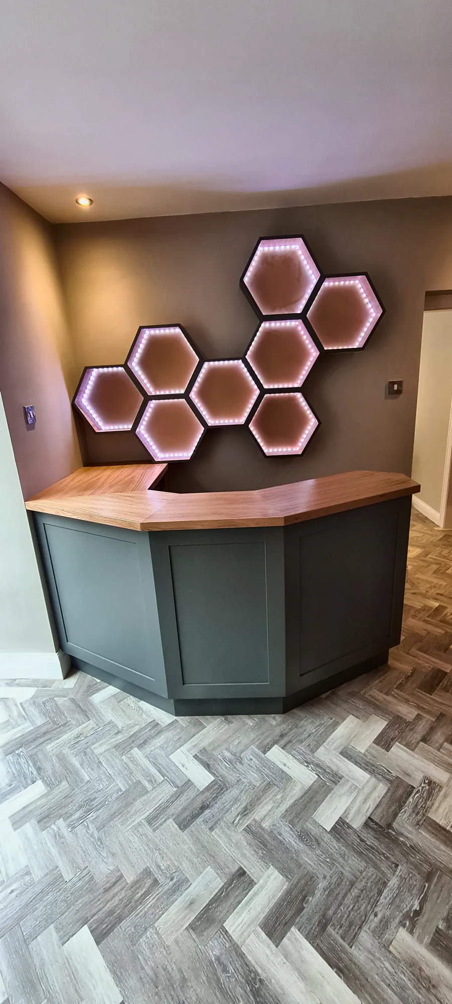 Curved home bar beneath lit honeycomb shelves