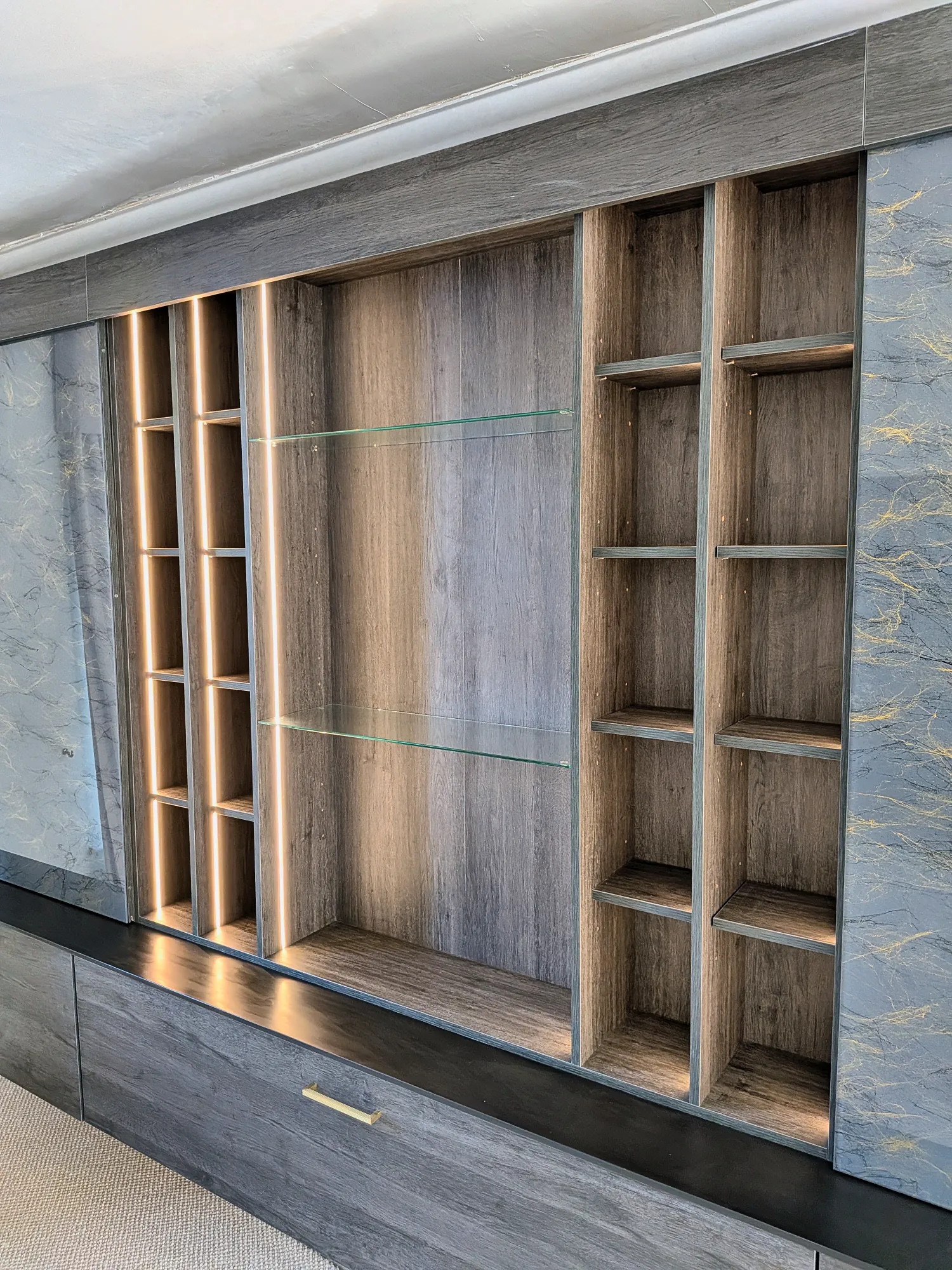Lit shelving and glass shelves between the marble-effect panels
