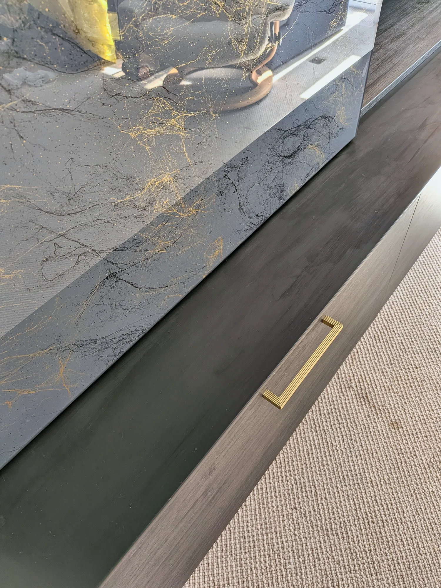 Brushed brass handle on a dark oak drawer front