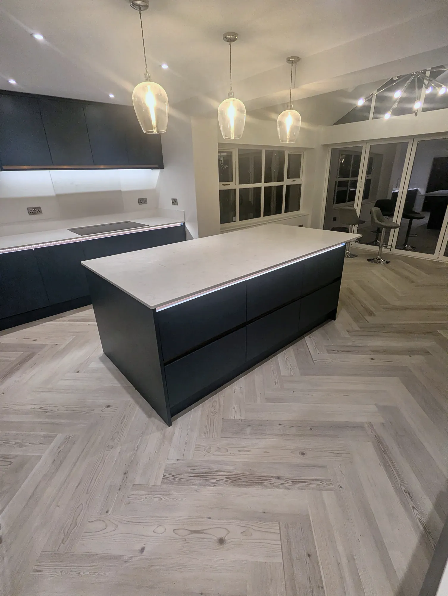 Navy handleless island on pale herringbone flooring