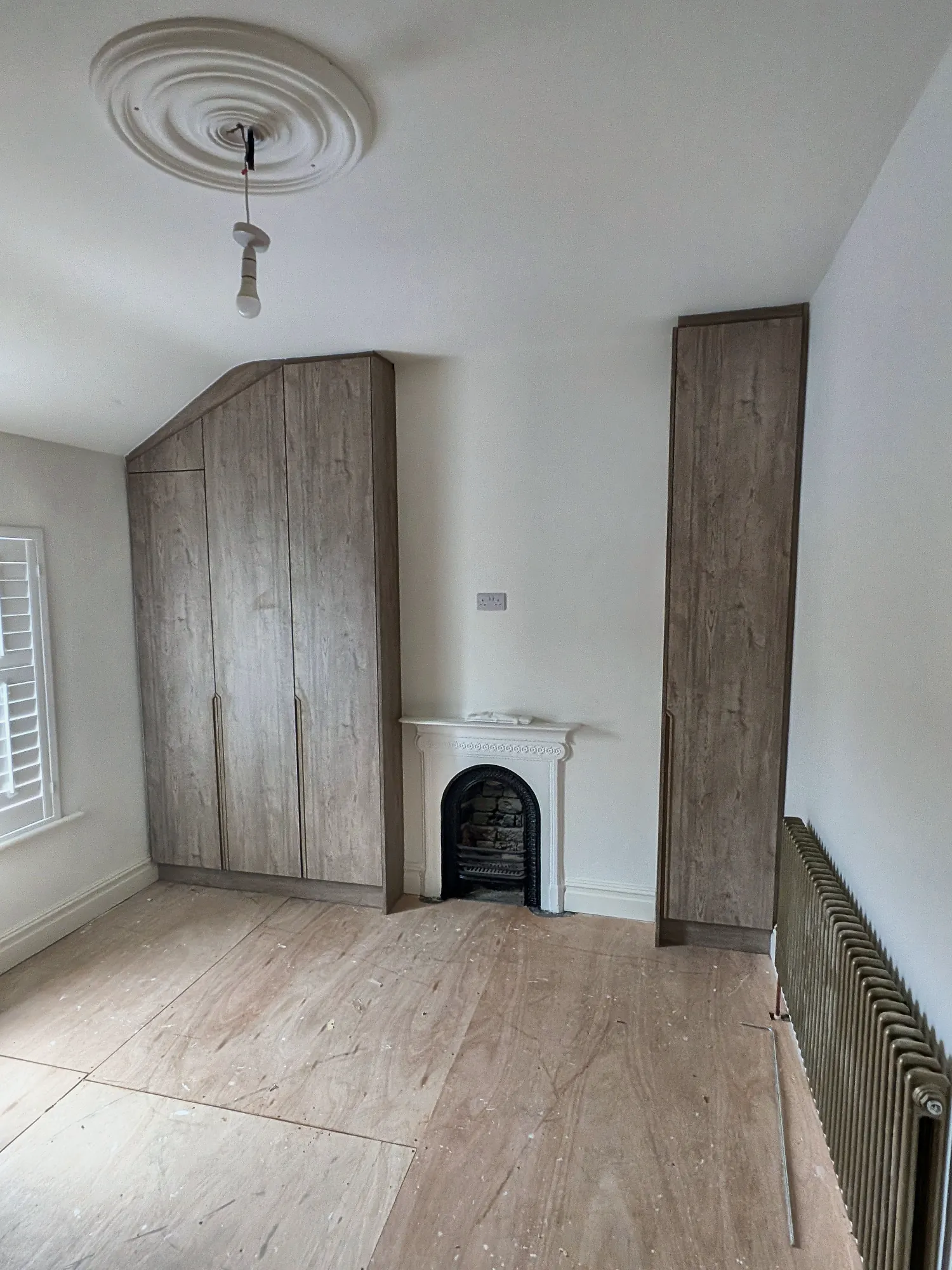 Fitted oak wardrobes either side of a period fireplace