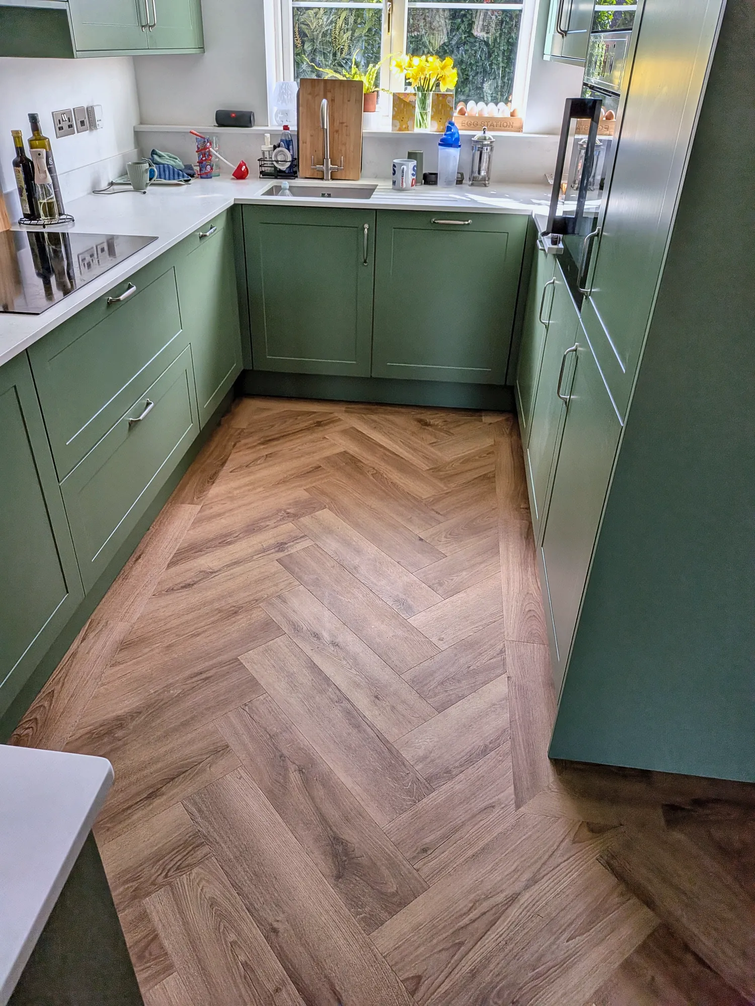 Sage green Shaker kitchen on herringbone flooring